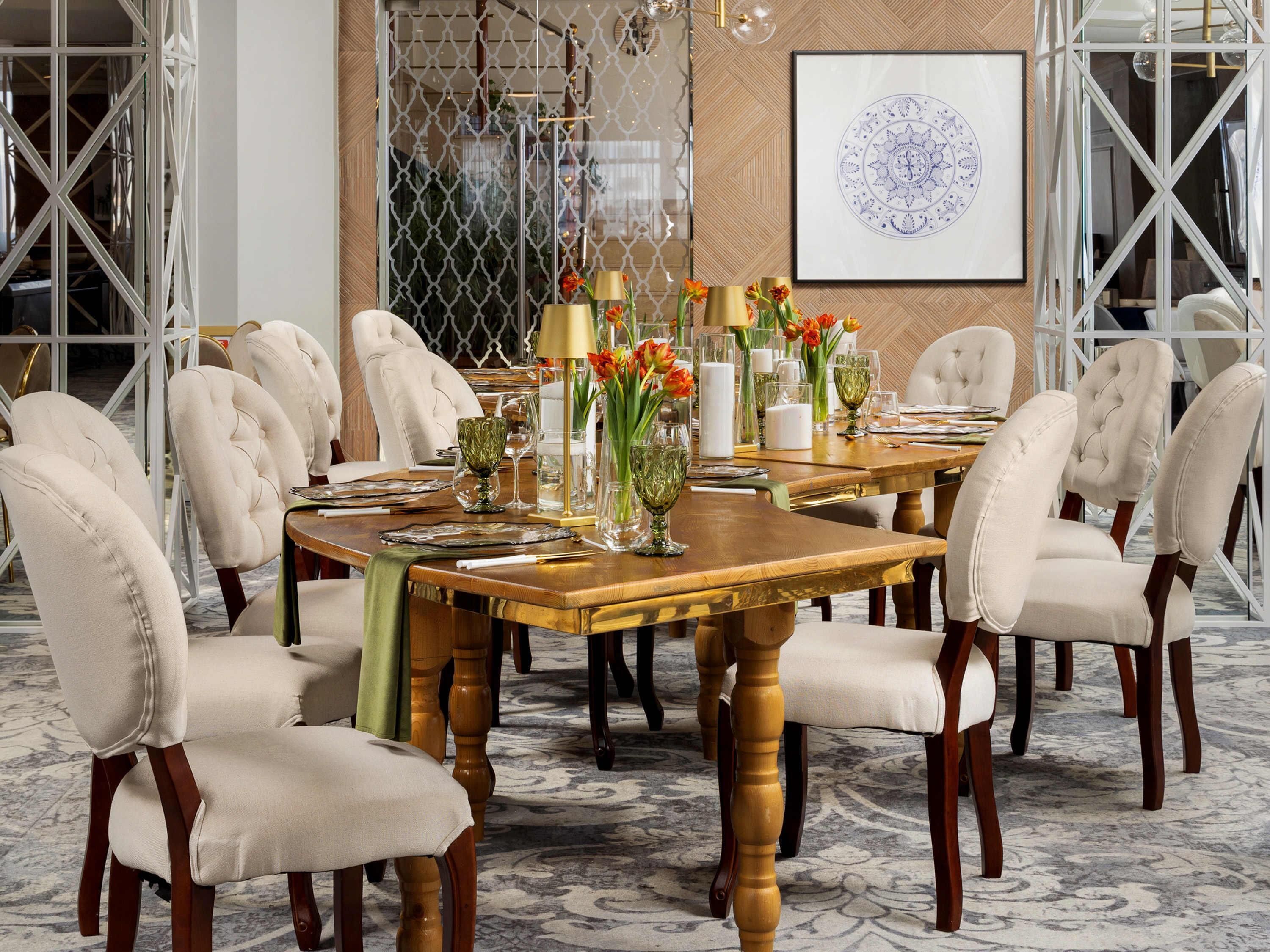 Uma sala de jantar formal com uma longa mesa de madeira, cadeiras estofadas e um elemento decorativo na parede.