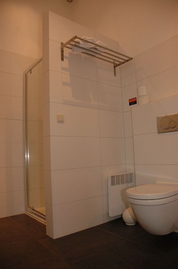 Un baño con cabina de ducha de vidrio, inodoro y perchero para toallas.