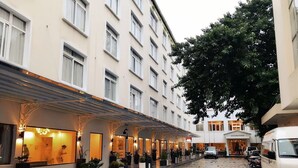Un hotel con pasarela techada, plantas en macetas y automóviles estacionados.