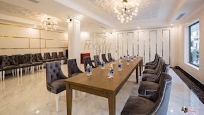 Un salón de conferencias con una larga mesa, varias sillas y un techo decorativo.