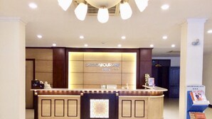 Un área de recepción con diseño moderno, que presenta un mostrador central con el nombre del hotel, 