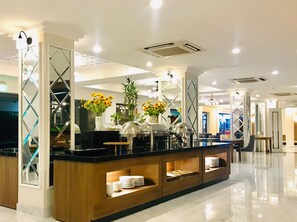 A modern hotel lobby with a central buffet area, glass partitions, and a polished floor. - Saigontourane Hotel (Da Nang)