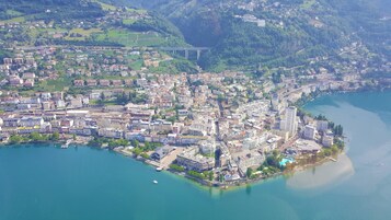 Vista aérea de una ciudad costera con densa construcción urbana, un puente destacado y un área frente al mar con edificios y zonas verdes.