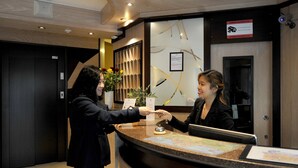 A reception desk with a map, a security sign, and a plant with flowers. - Hôtel Bon Port (Montreux)