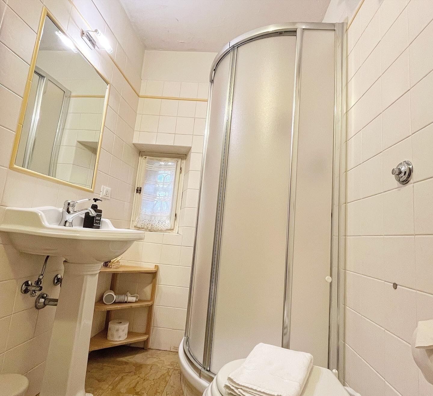 Une salle de bain avec un lavabo blanc, un miroir et une douche.