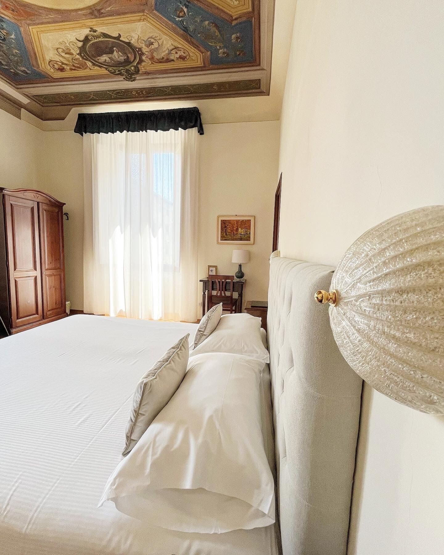 Une chambre d’hôtel avec un grand lit, une armoire en bois, un bureau avec une lampe et un tableau au mur.