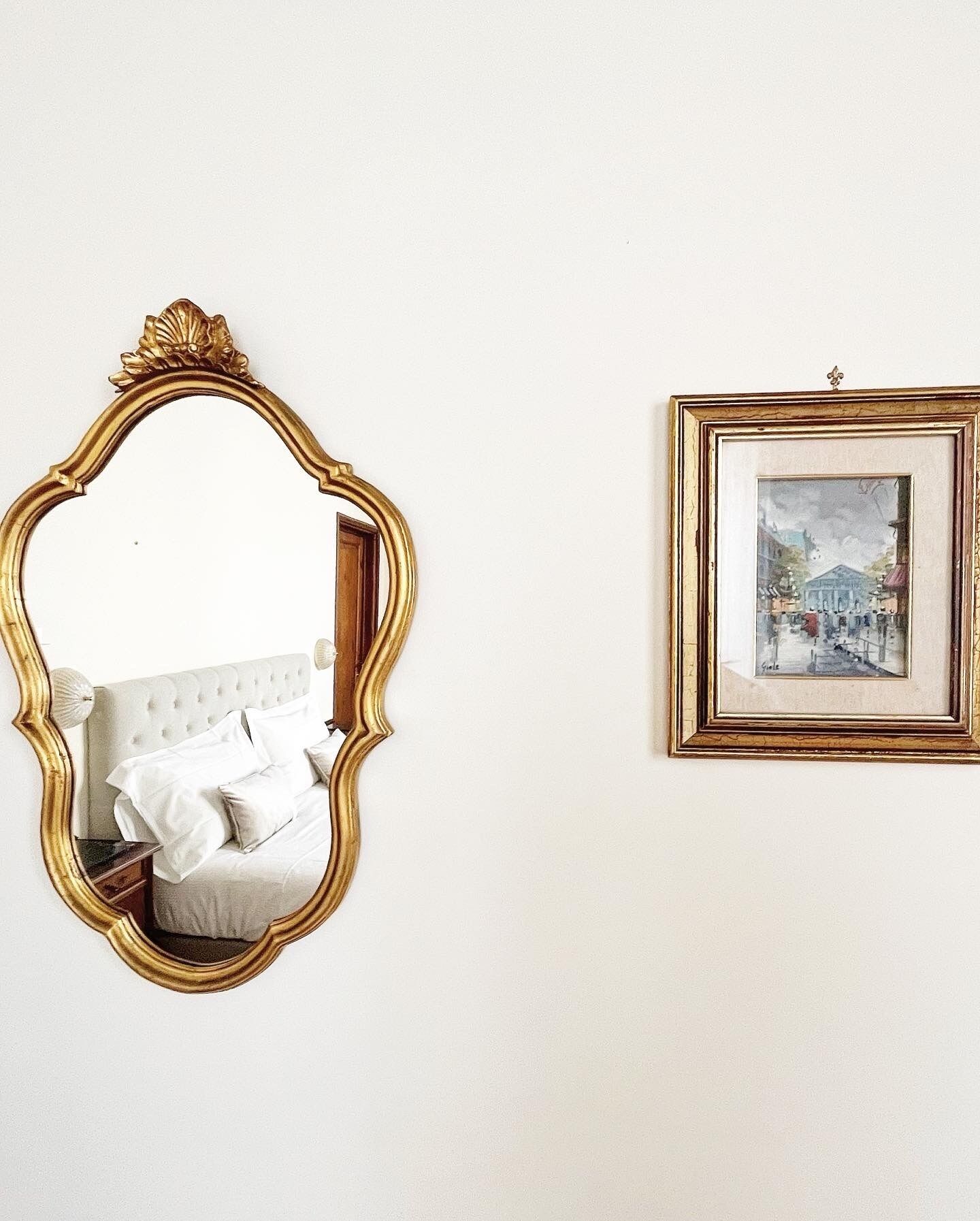 Una habitación con un espejo grande y ornamentado y un cuadro en la pared.