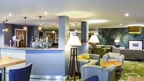 A hotel lobby with a bar area, seating arrangements, and a green patterned carpet. - Mercure Newbury West Grange Hotel (Thatcham)