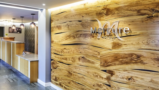 A reception area with a wooden wall and a sign that reads "Merre Hotels". - Mercure Newbury West Grange Hotel (Thatcham)