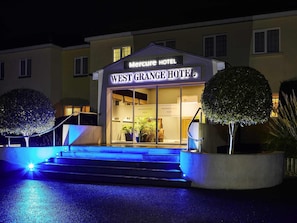 L'ingresso dell'Hotel West Grange, con un cartello, gradini e piante in vaso.
