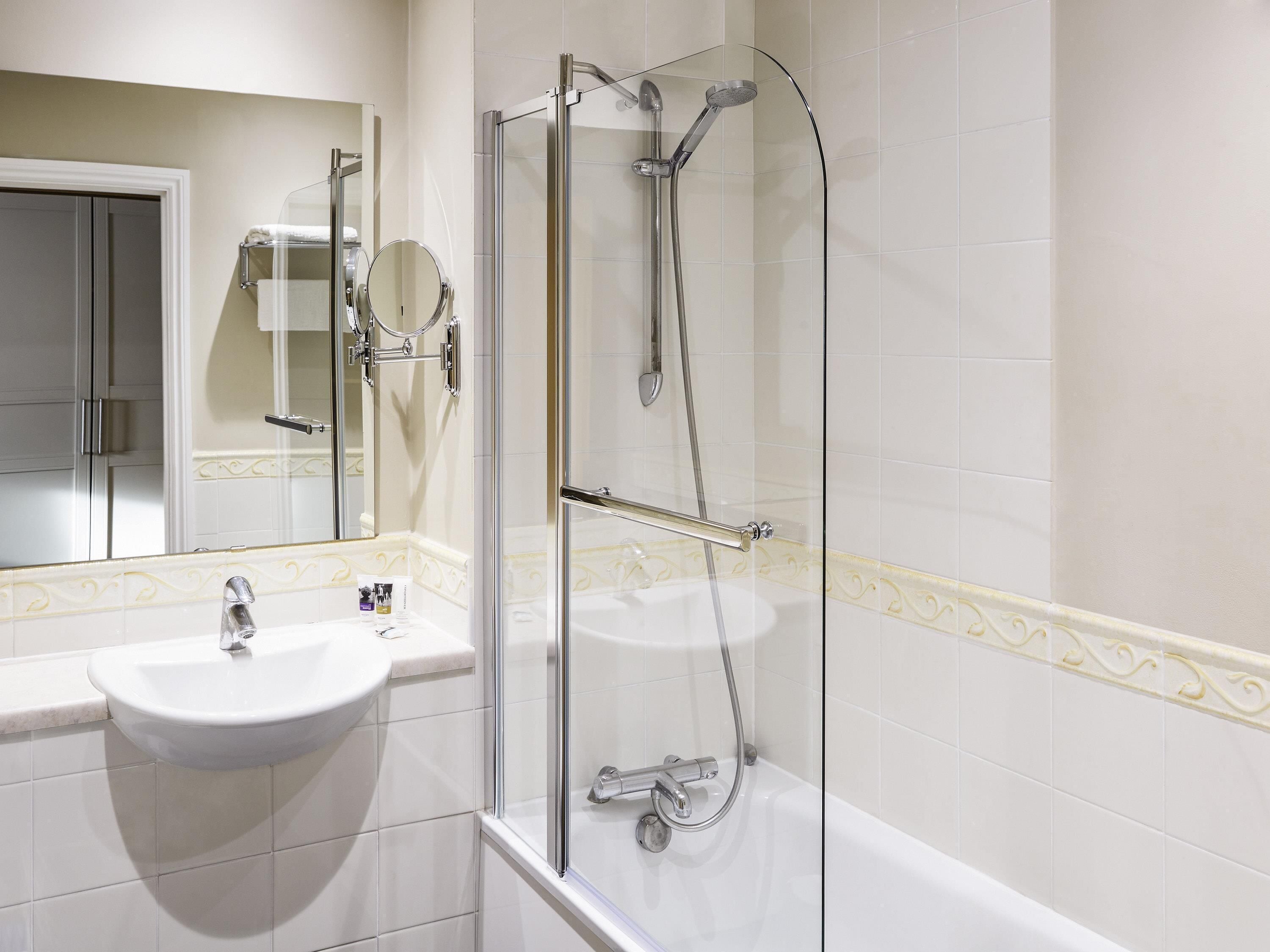 A bathroom with a glass-enclosed shower, a sink, and a mirror.
