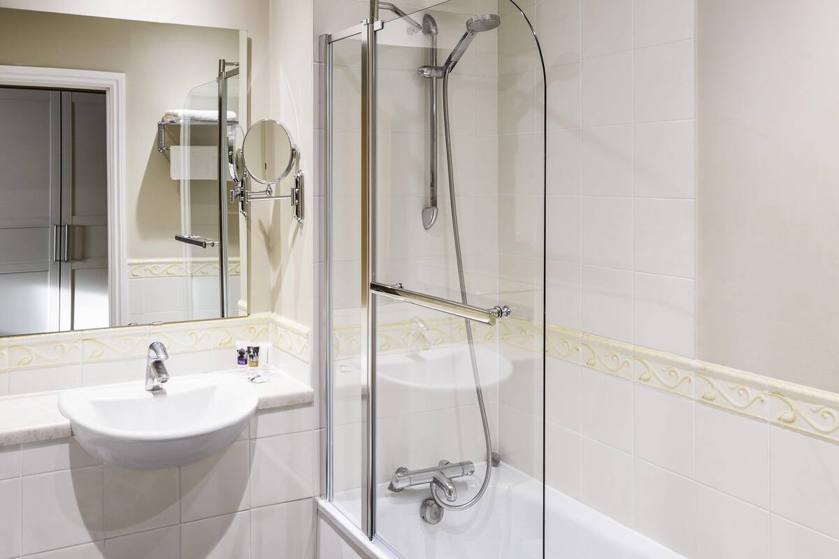Un baño con ducha de vidrio, lavamanos y espejo.