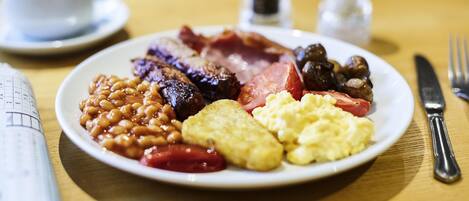 A plate of breakfast food including sausages, beans, eggs, and tomatoes.