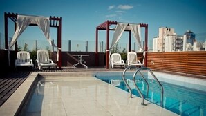 A rooftop pool area with two white lounge chairs and a small table, surrounded by a wooden deck and a cityscape view. - Hotel del Fundador (Córdoba)
