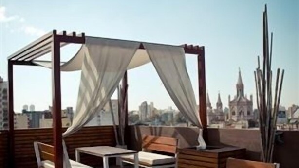 A rooftop terrace with wooden flooring, white cushioned chairs, and a canopy structure. - Hotel del Fundador (Córdoba)