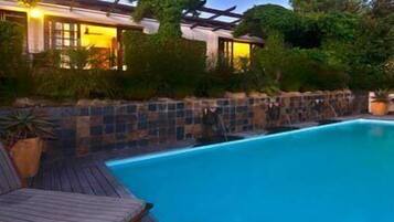 A swimming pool with a wooden deck and a pergola.