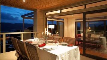 A dining area with a table set for four, a candelabra centerpiece, and a view of the outdoors.