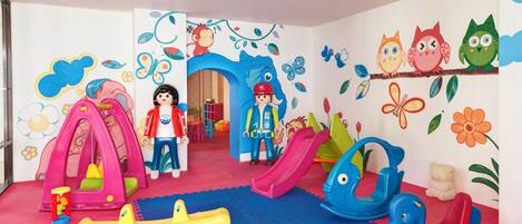 A children's playroom with colorful toys, a slide, and playful wall decorations.
