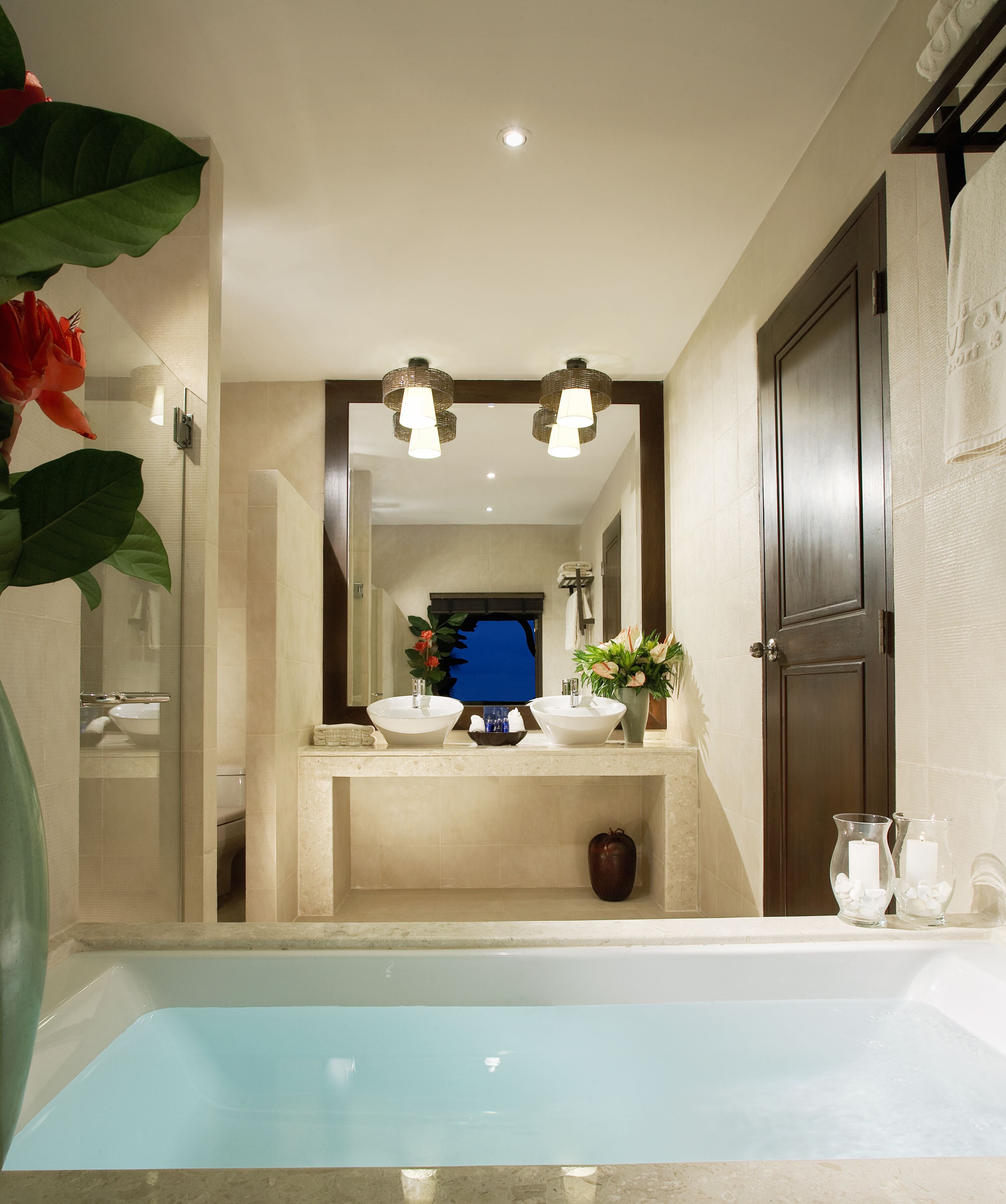 Un baño moderno con bañera, dos lavamanos, un espejo grande y una puerta.
