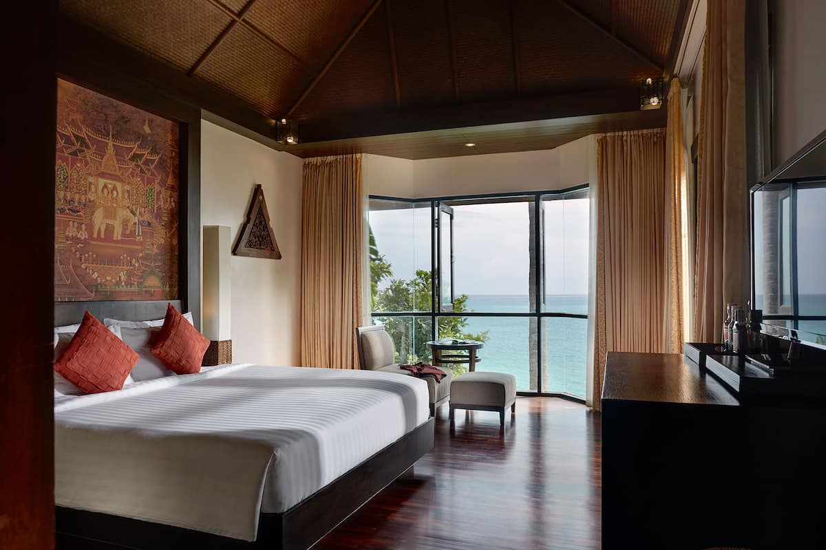 A spacious bedroom with a large bed, a desk, and a view of the ocean.