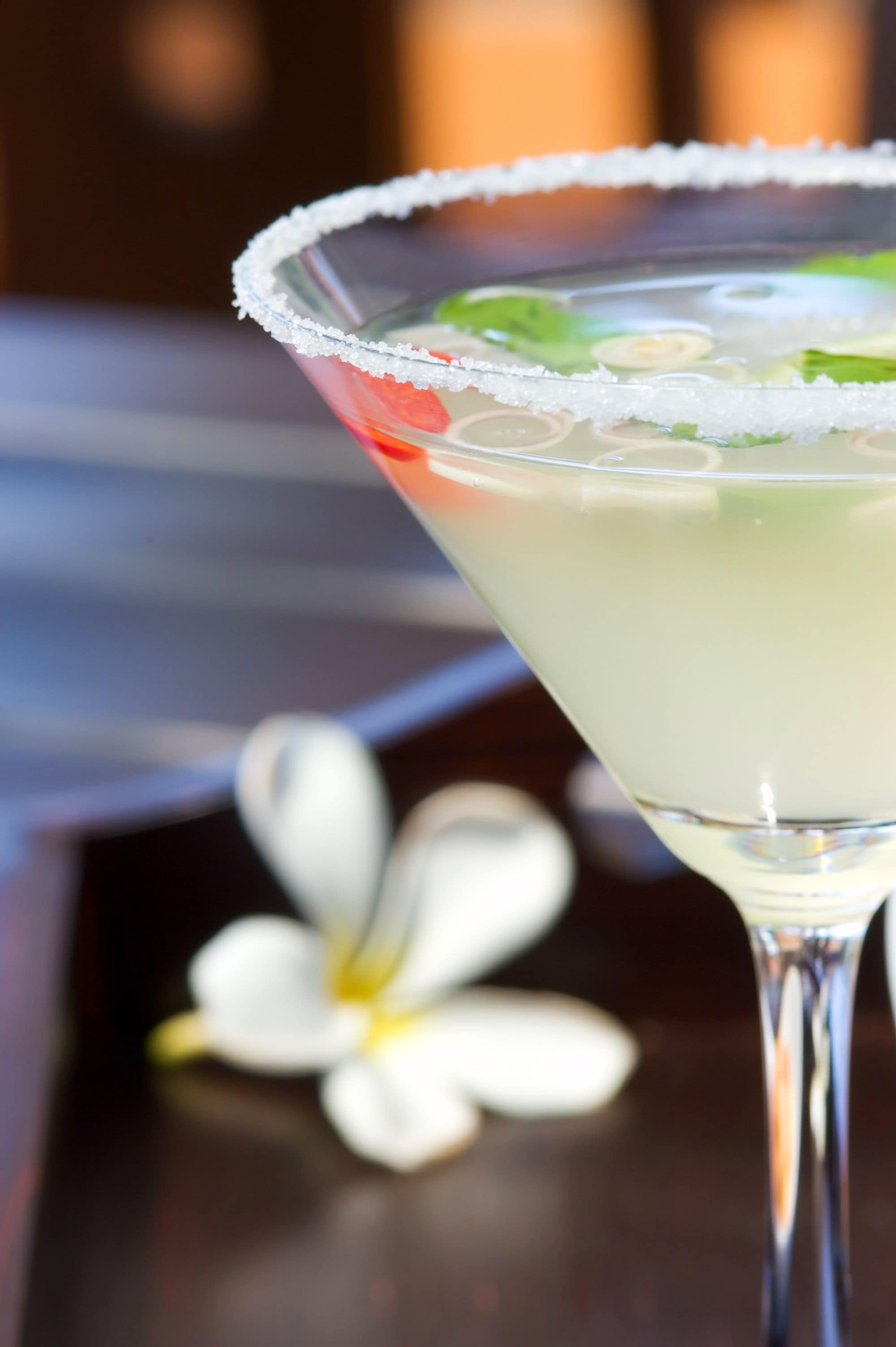Un verre à martini dont le bord est saupoudré de sel et qui est décoré d’une tranche de citron vert et d’une cerise.