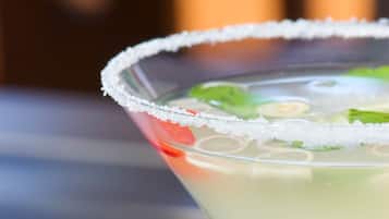 Un verre à martini dont le bord est saupoudré de sel et qui est décoré d’une tranche de citron vert et d’une cerise.
