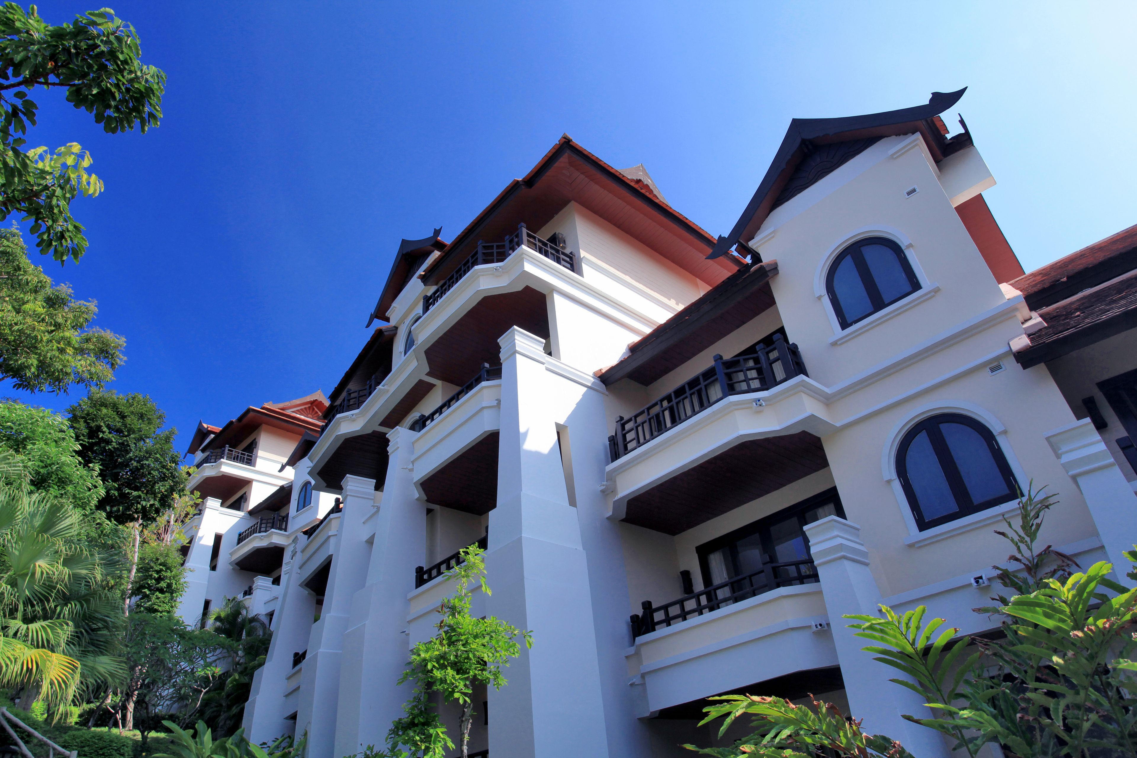 A multi-story hotel with balconies and a red roof.