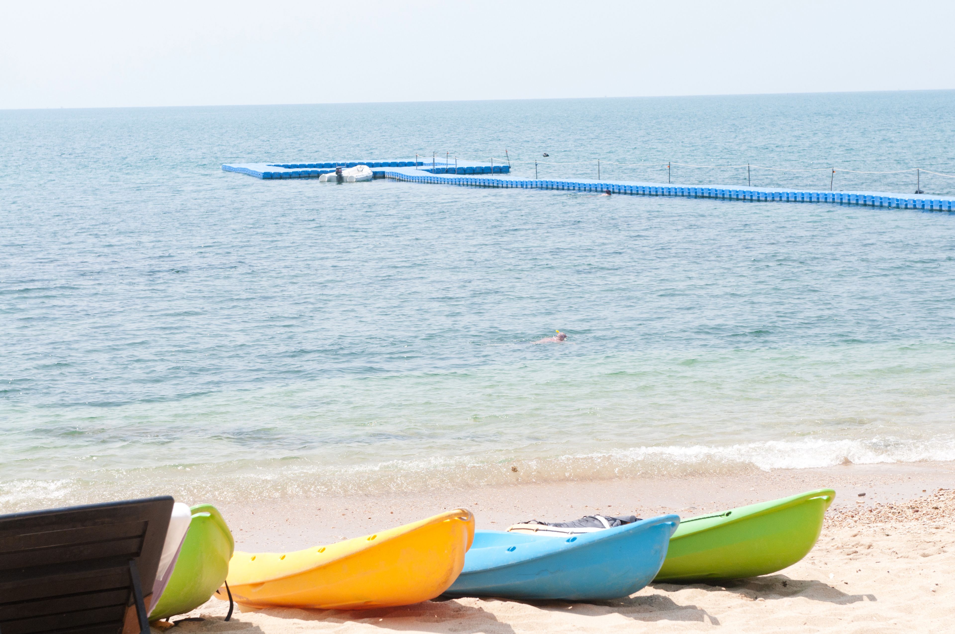 A beach with kayaks and a pier extending into the water.