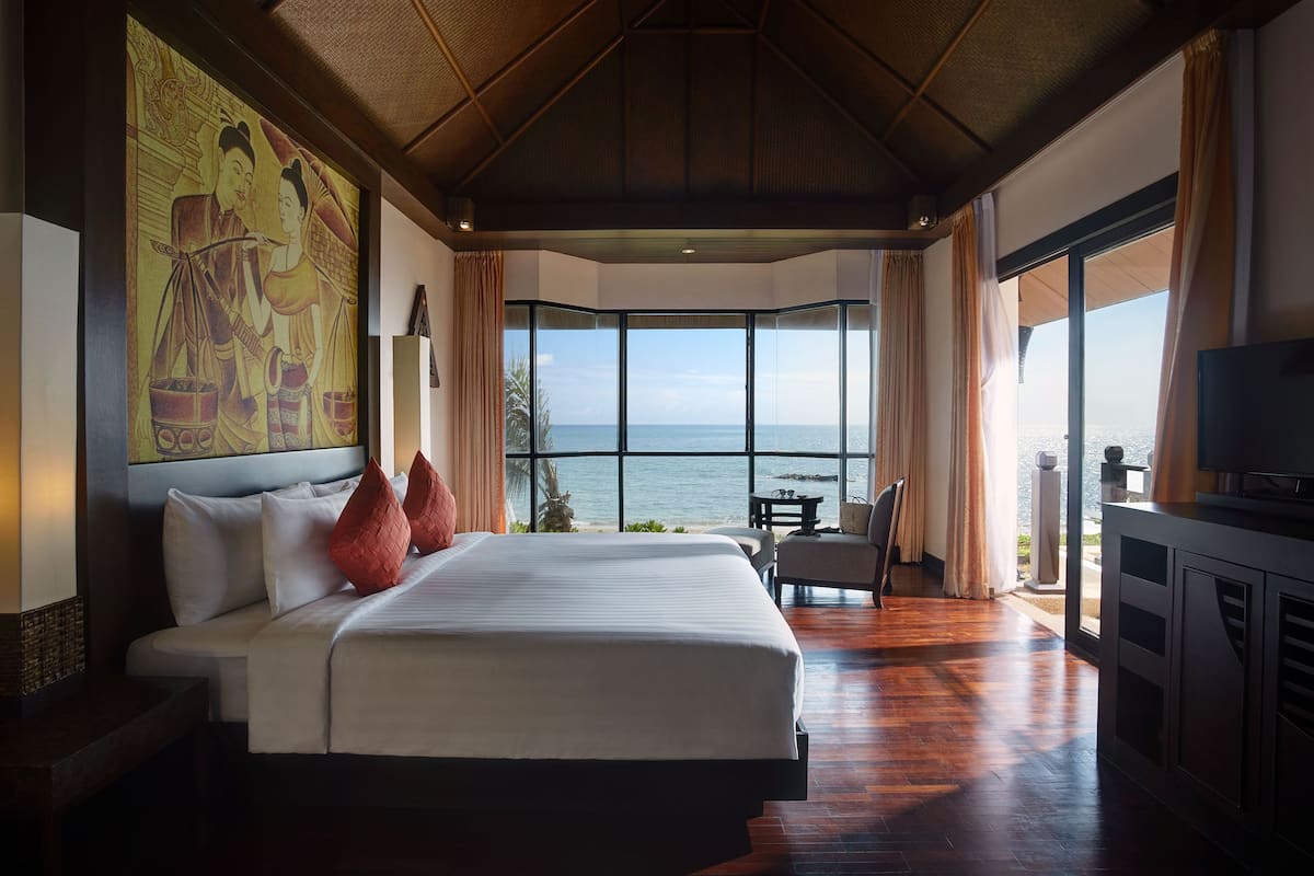 A spacious bedroom with a large bed, a television, and a view of the ocean.