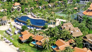 An aerial view of a resort with multiple bungalow-style buildings, a large swimming pool, and a beach with boats. - Rawi Warin Resort and Spa (Ko Lanta)