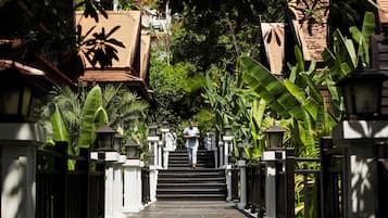 A person walking up a series of steps surrounded by lush greenery and traditional architecture.