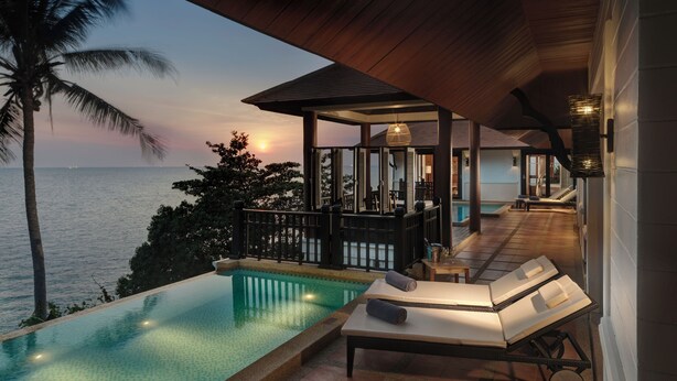 An infinity pool with a view of the ocean at sunset, a lounge area with a table and chairs, and a covered patio with a pool table. - Rawi Warin Resort and Spa (Ko Lanta)