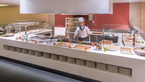 Un bufé con diversos platos y un cocinero preparando comida.