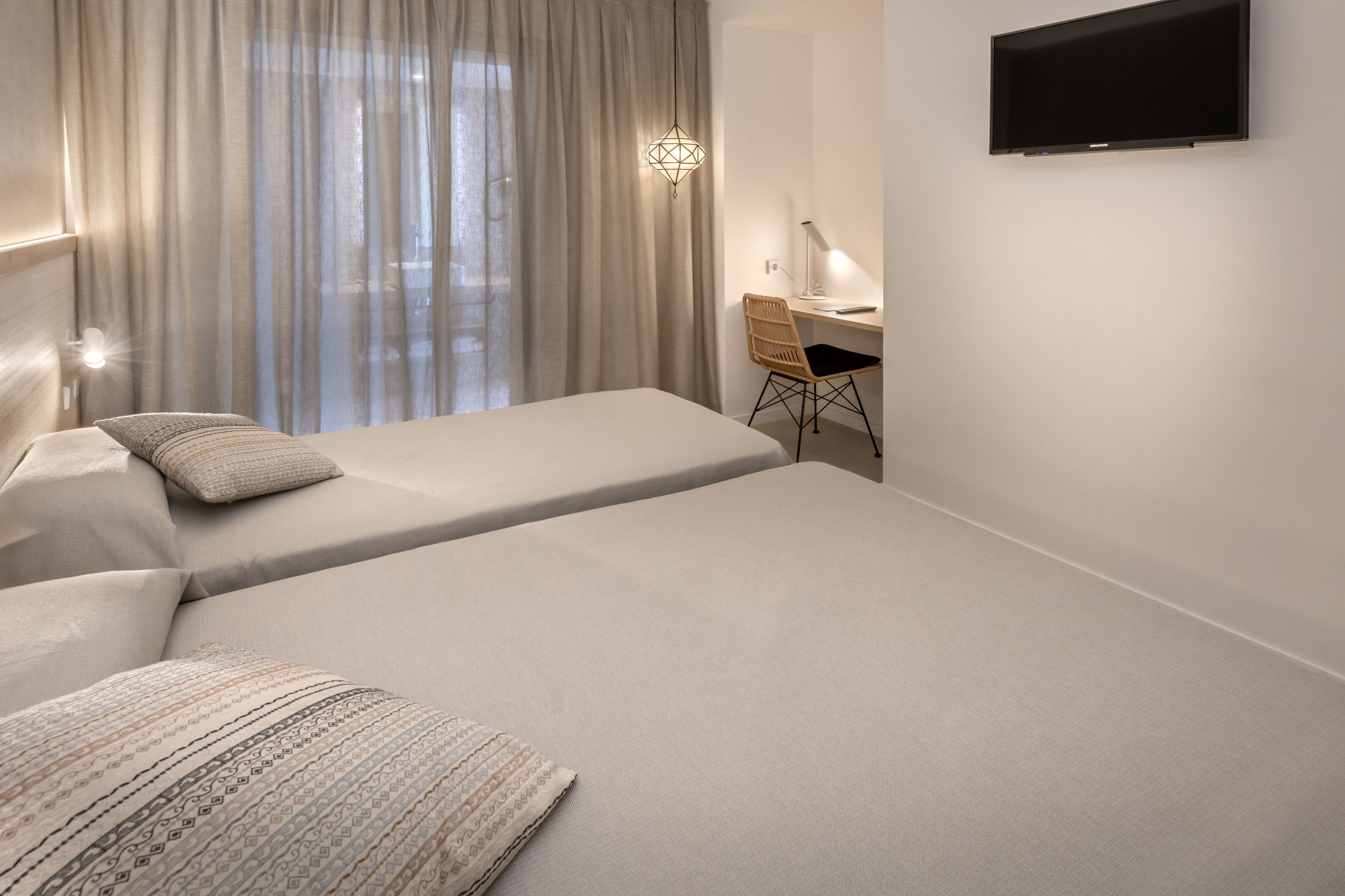 Una habitación de hotel moderna con dos camas, un escritorio y un televisor.