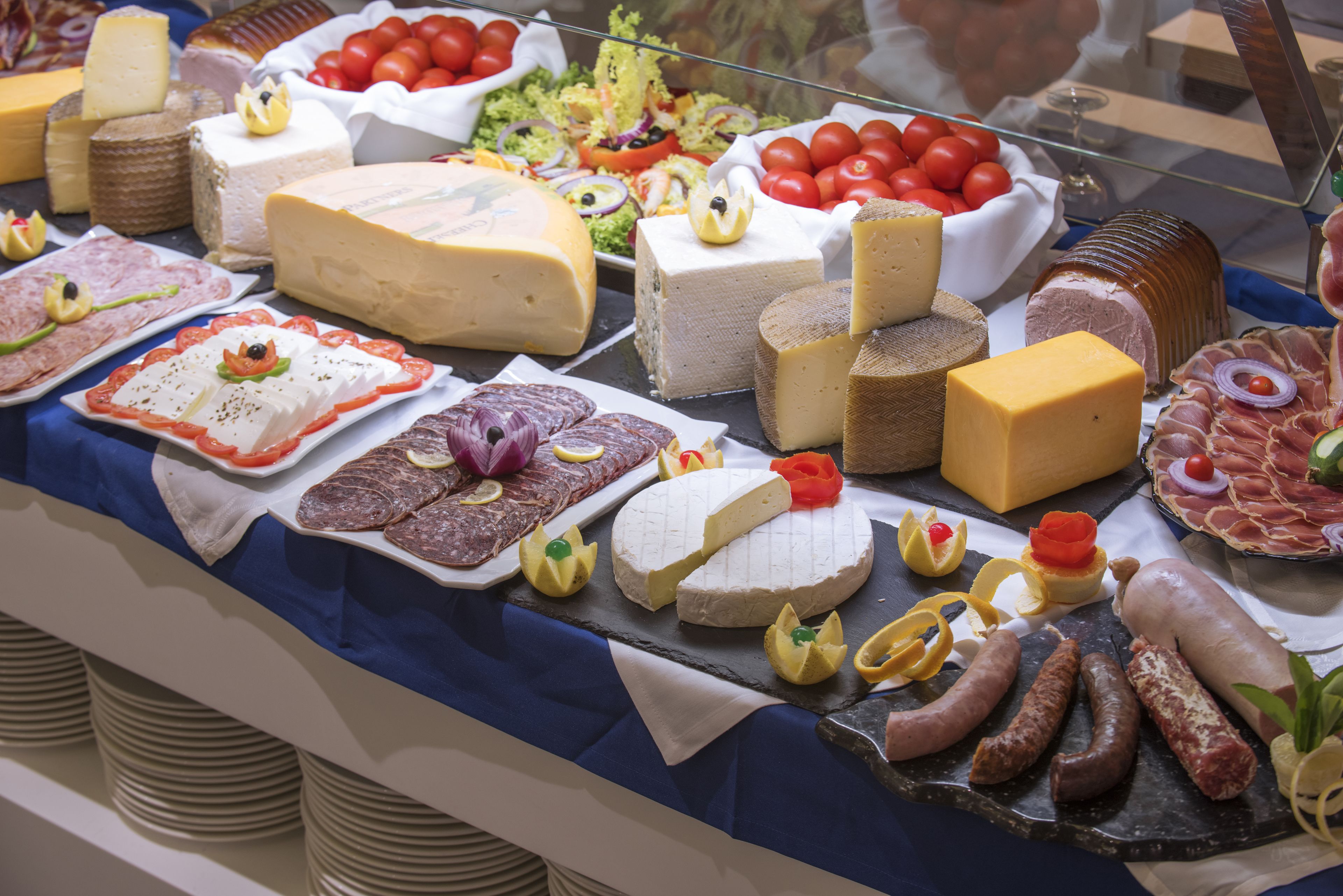 Un assortiment de fromages, de charcuteries et de salades est présenté sur une table de buffet.