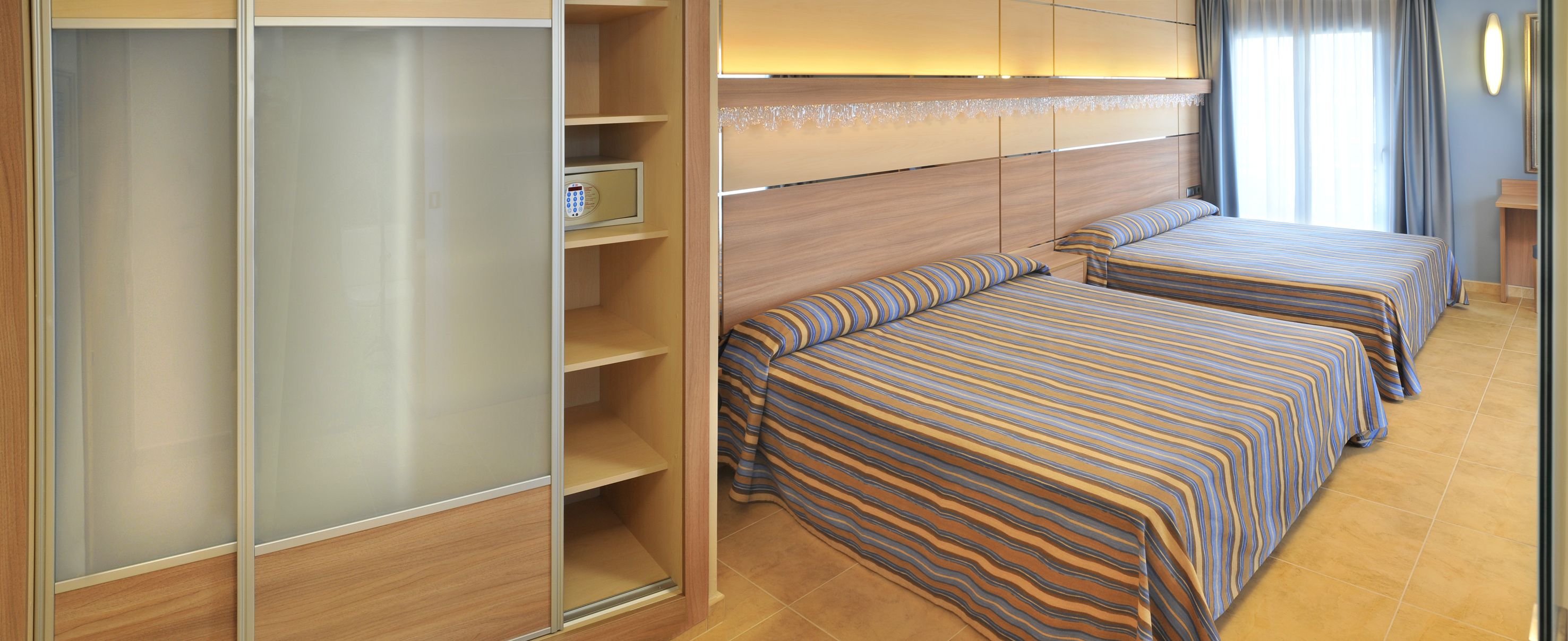 A hotel room with two beds, a wardrobe, and a vanity area.