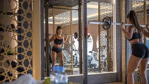 Un gimnasio con equipo de ejercicio, un espejo y una pared con diseño geométrico.