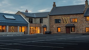 A hotel with a stone facade, large illuminated letters 'W' and 'S', and a parking lot in front. - Wainstones Hotel (Middlesbrough)