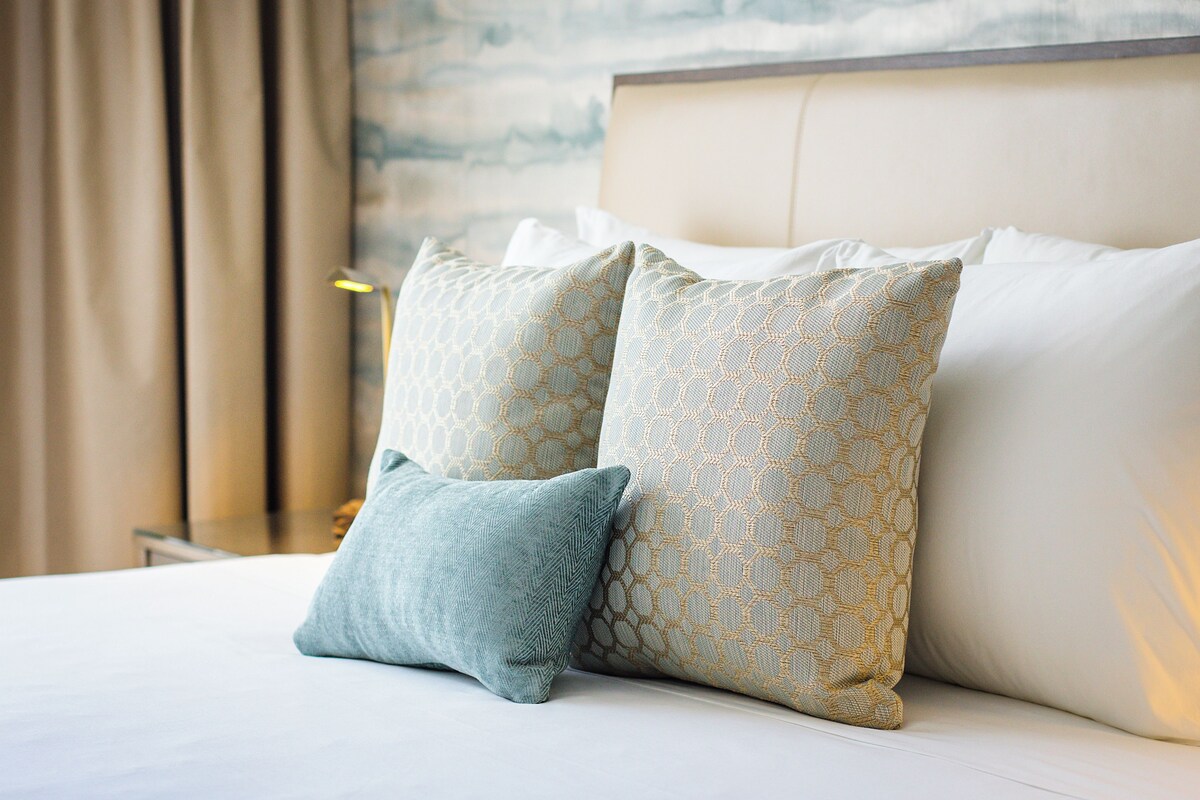 A neatly made bed with patterned pillows and a headboard.