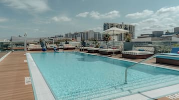 Una piscina al aire libre, sombrillas, sillones reclinables de piscina