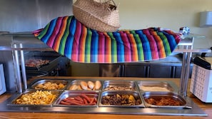 Een buffet met diverse gerechten, waaronder hotdogs, friet en andere maaltijden.