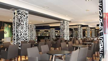 Un interior moderno con techos altos, columnas con diseño y una zona de bar al fondo.