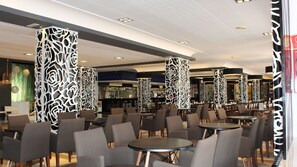 A modern interior with high ceilings, patterned columns, and a bar area in the background. - Evenia Olympic Resort (Lloret de Mar)