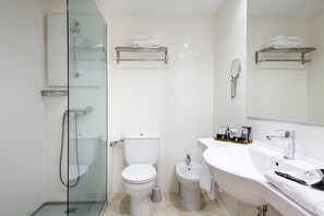 Ein modernes Badezimmer mit einer Duschkabine, einer Toilette, einem Bidet und einem Waschbecken mit Spiegel.