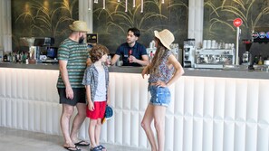 Un espace bar avec un comptoir, des tabourets de bar et une personne qui sert des boissons.