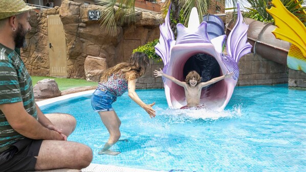 A pool with a water slide and a rock wall. - Evenia Olympic Resort (Lloret de Mar)