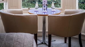 A room with a table and chairs by a large window with a view of greenery and houses. - Ambleside Townhouse (Ambleside)