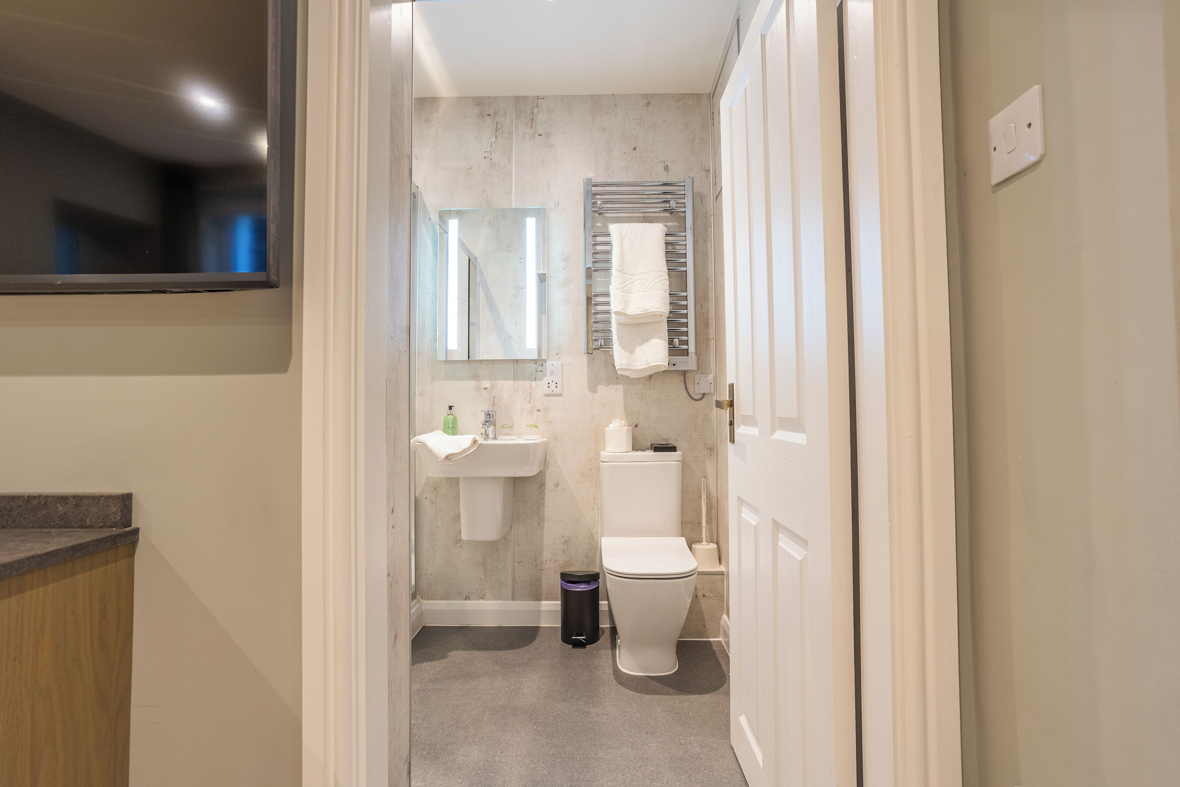 A modern bathroom with a toilet, sink, and towel rack.
