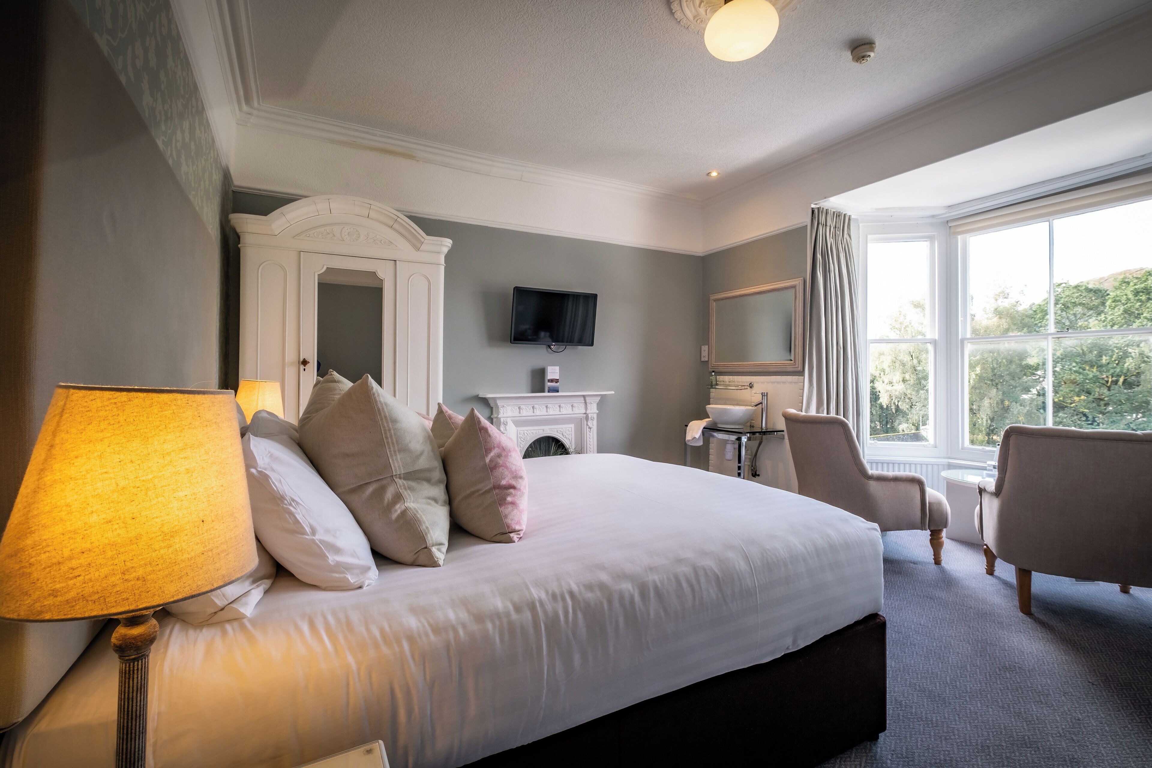 A hotel bedroom with a large bed, a television, a fireplace, and a view of the outdoors.
