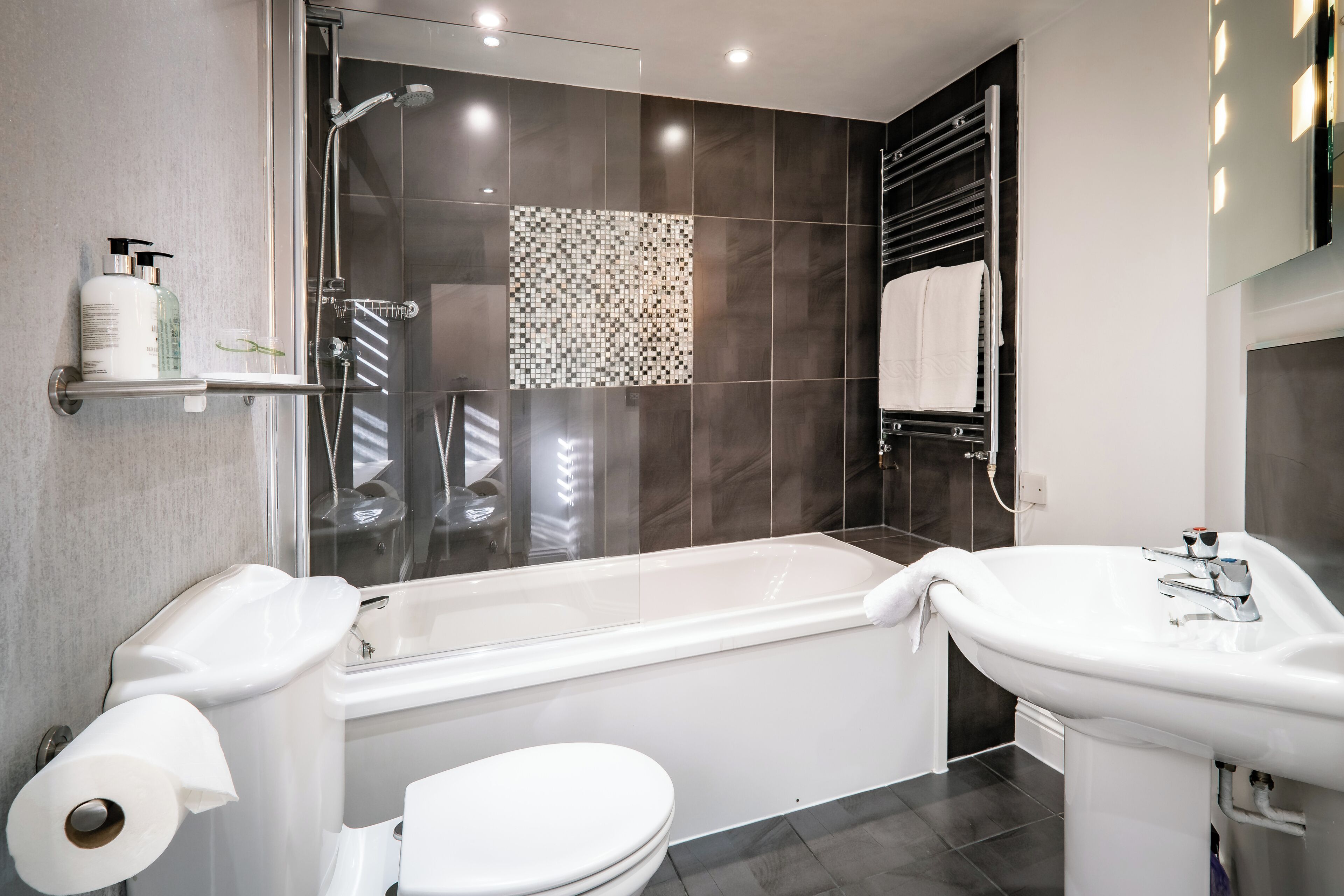 A modern bathroom with a bathtub, toilet, and sink.
